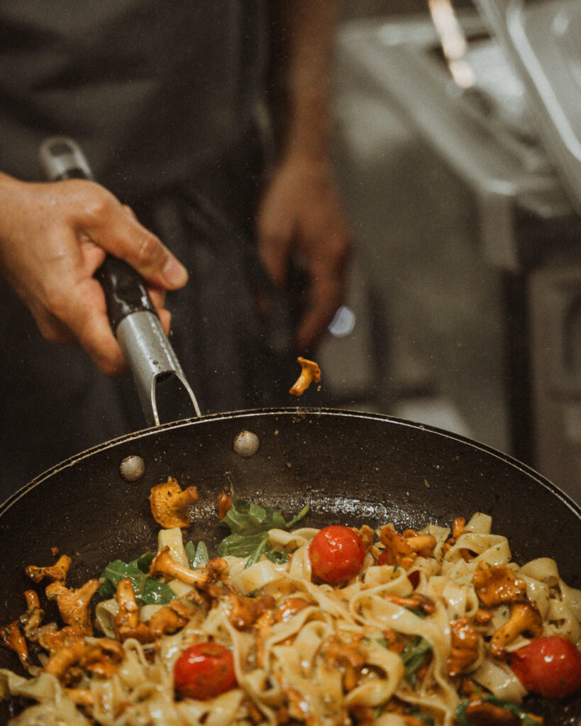Pfifferlinge und Nudeln werden in Pfanne geschwenkt