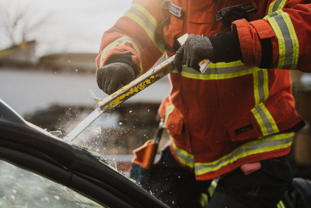 Modernes Lifestyle- und Businessfoto von einem Feuerwehrmann im Kreis Konstanz wie er eine Autoscheibe einschneidet.